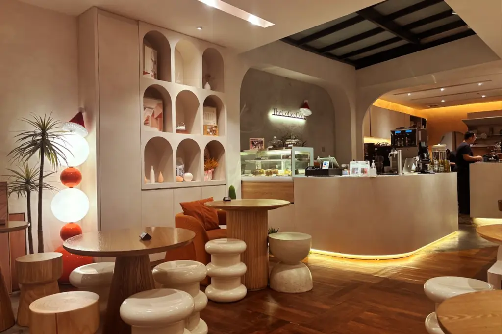 An interior view of The Coffee Code Singapore showcasing a warm, earthy aesthetic with arched shelving, a clean counter area, and comfortable, modern seating.