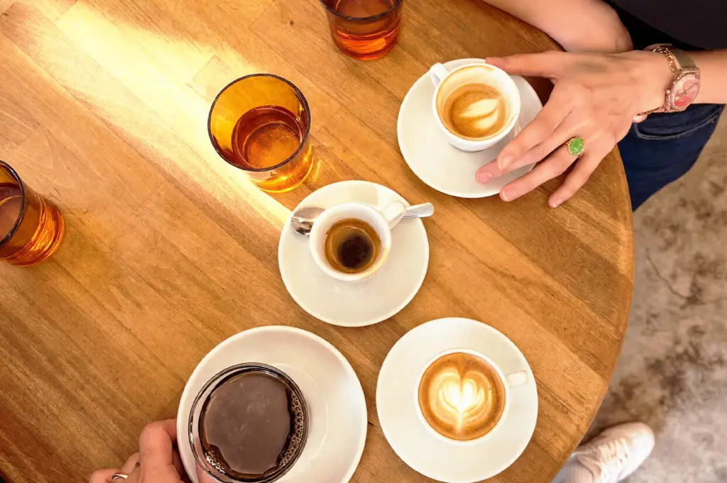 A high-angle view of specialty coffee served on a wooden table at Nylon Coffee Roasters in Everton Park, including cups of espresso and lattes enjoyed by customers.