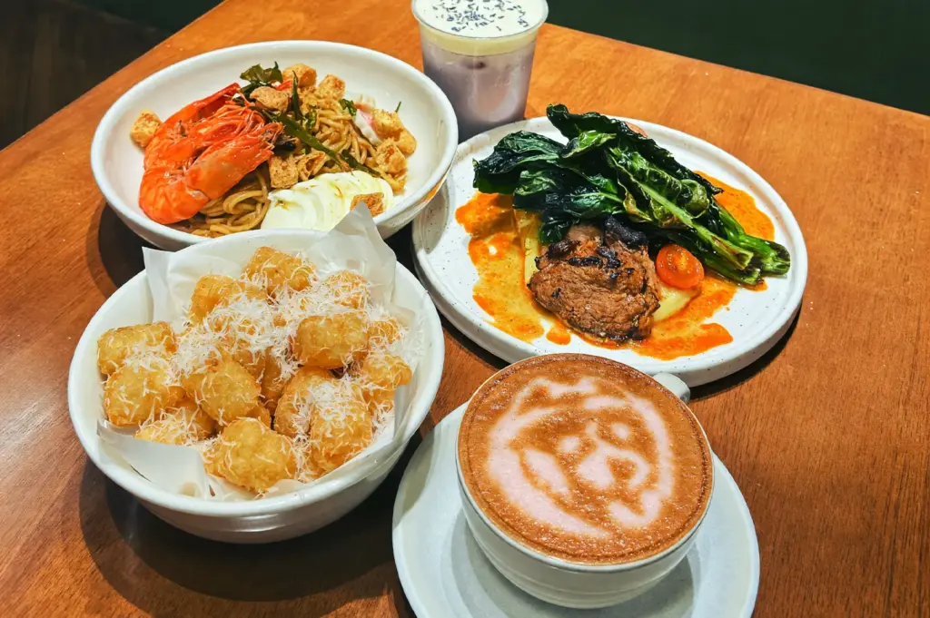 A variety of savory dish items including laksa cream spaghetti with large prawns, cauliflower steak, a bowl of crispy tofu puffs, and a signature latte to follow at Acoustics Coffee Bar.