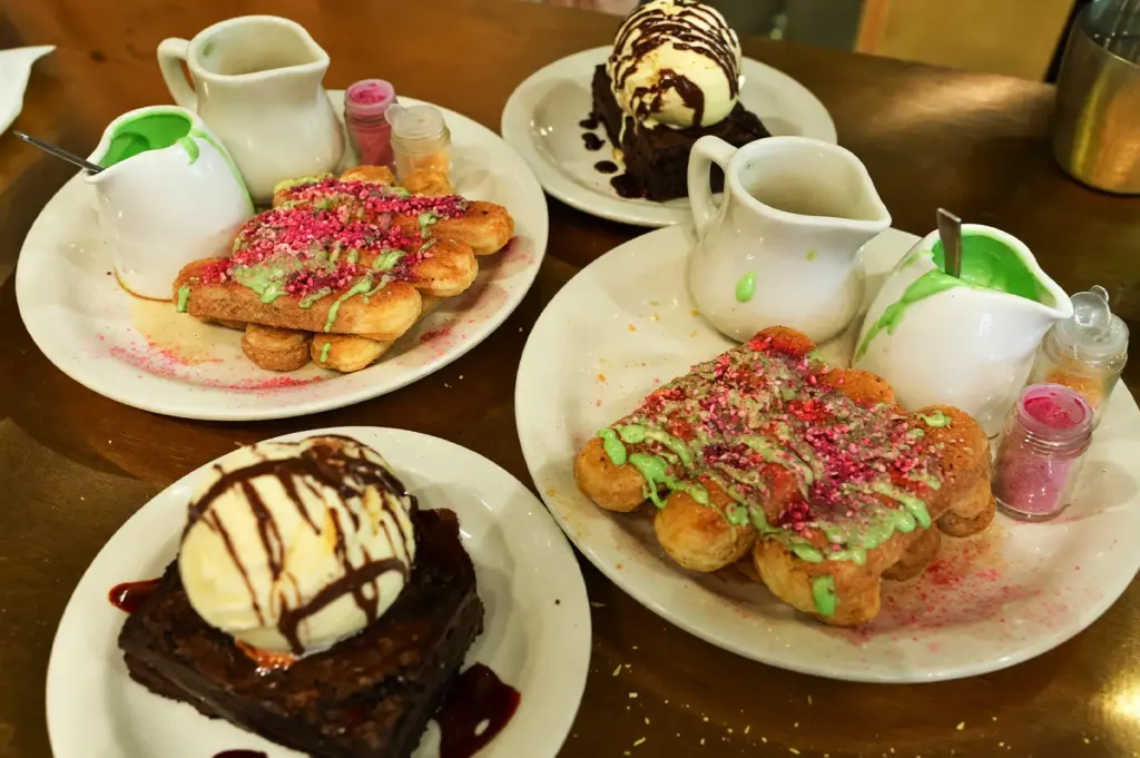 Gourmet desserts at Acoustics Coffee Bar, showcasing pandan tiramisu with colorful toppings and rich chocolate brownies served with vanilla ice cream.