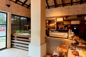 Interior view of Burnt Ends Bakery in Singapore, featuring a modern service counter with a professional espresso machine, display cases filled with artisan pastries, and a rustic tiled wall.