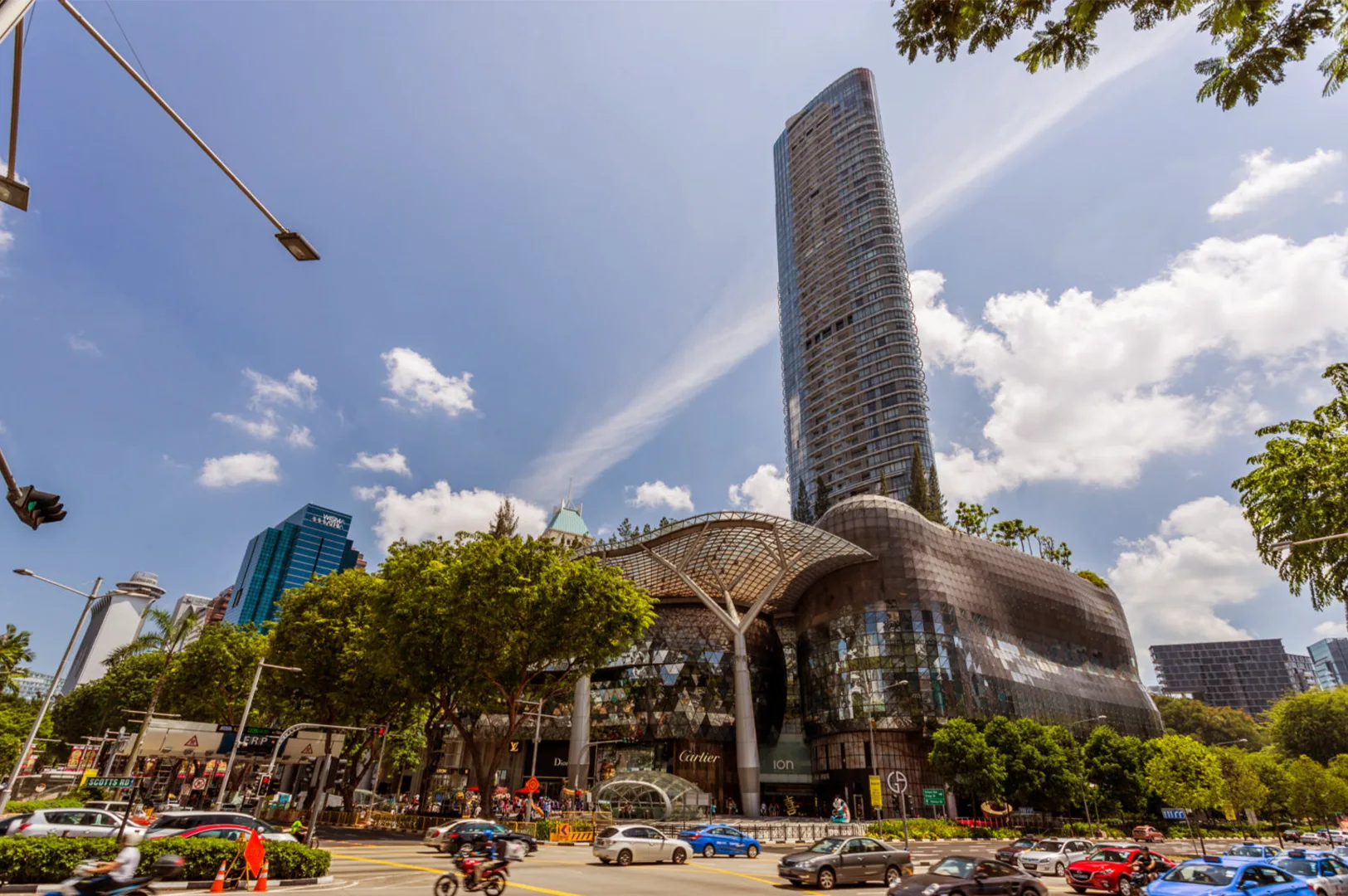 A vibrant street-level view of the iconic Orchard Road skyline in Singapore, showcasing modern skyscrapers and bustling city life, representing a premier destination for cafe hopping and to taste Orchard Road delicacies.