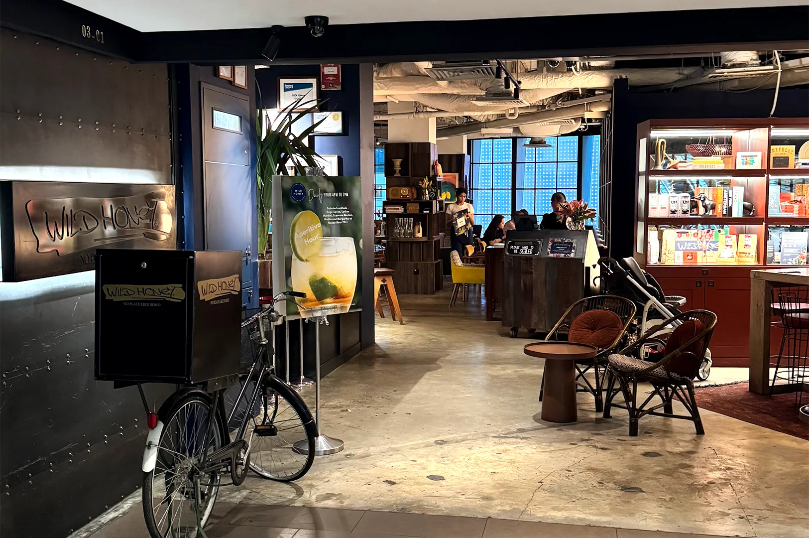 Entrance to Wild Honey Cafe at Mandarin Gallery, Singapore, featuring their signature bicycle branding and a welcoming, cozy interior designed for an all-day brunch experience.