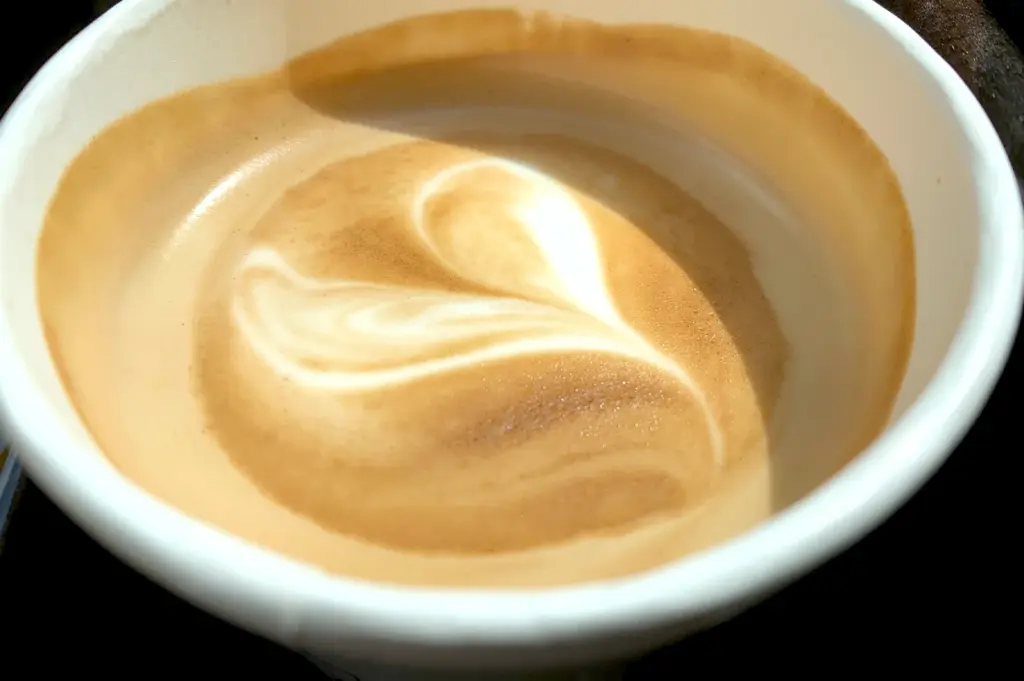 A top-down view of a smooth, creamy latte with beautiful heart-shaped latte art, representing the cafe experience for decaf coffee drinkers.