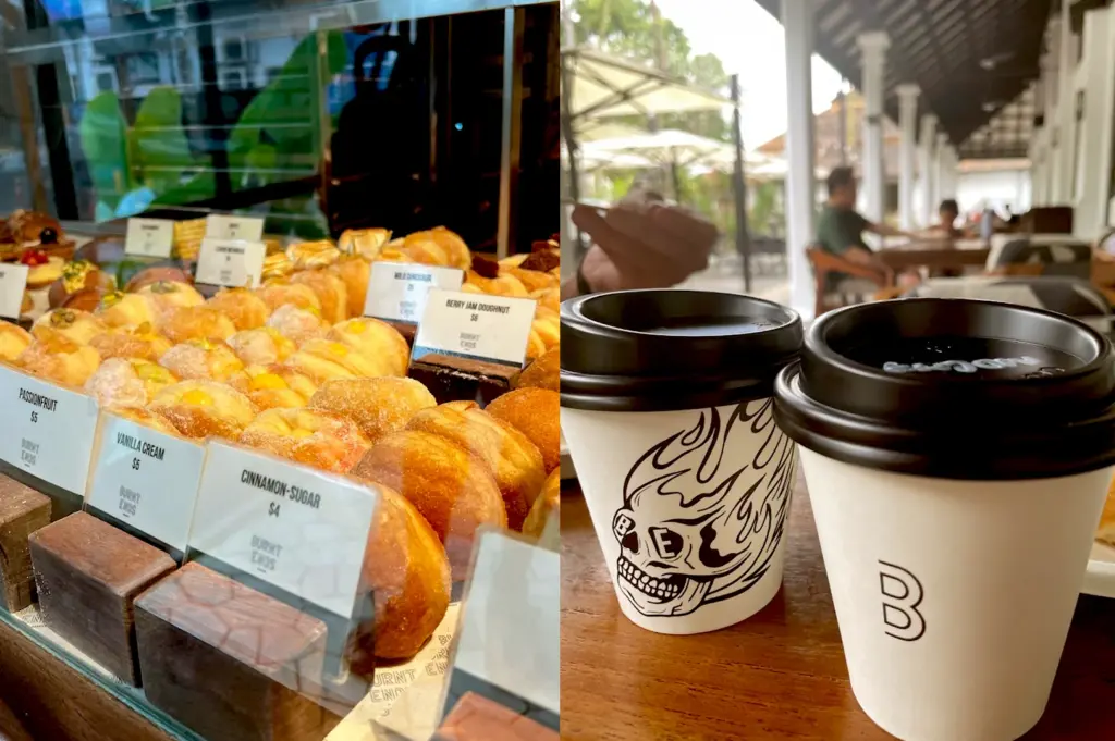 Close-up of the pastry display at Burnt Ends Bakery showcasing a variety of artisan doughnuts like Berry Jam and Cinnamon-Sugar, with takeaway coffee cups in the foreground.
