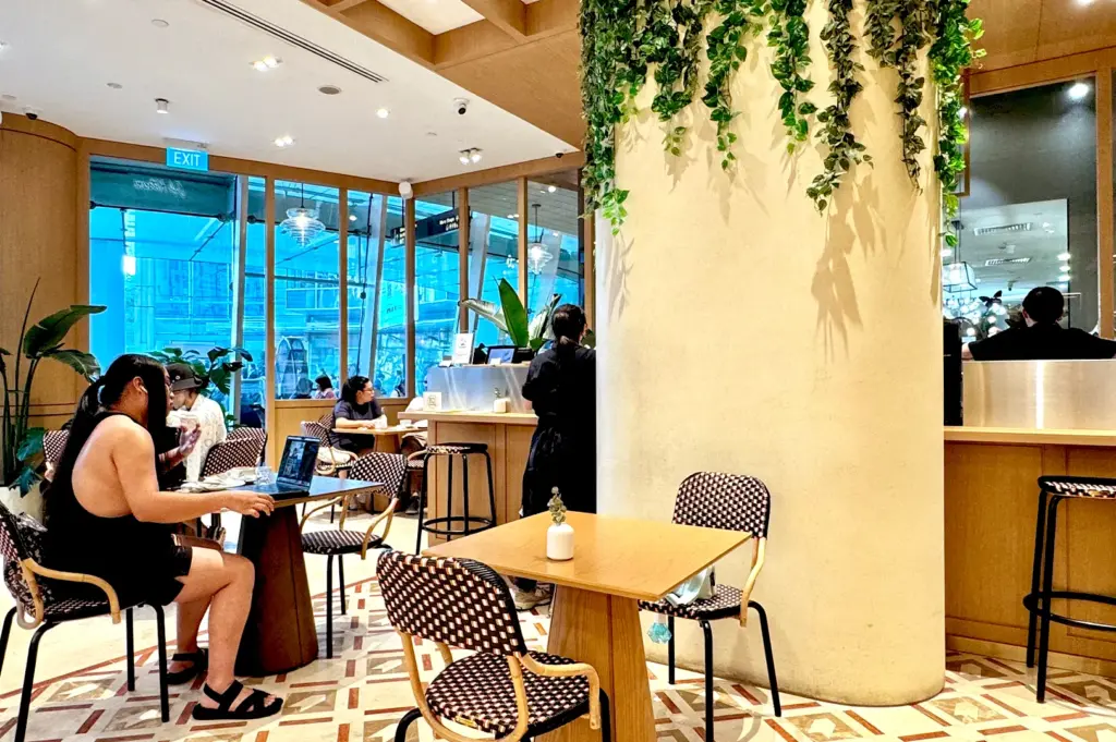 Interior dining area of Café Kitsuné Singapore, showing customers enjoying the comfortable seating, elegant decor, and relaxing ambiance of the popular Capitol venue.