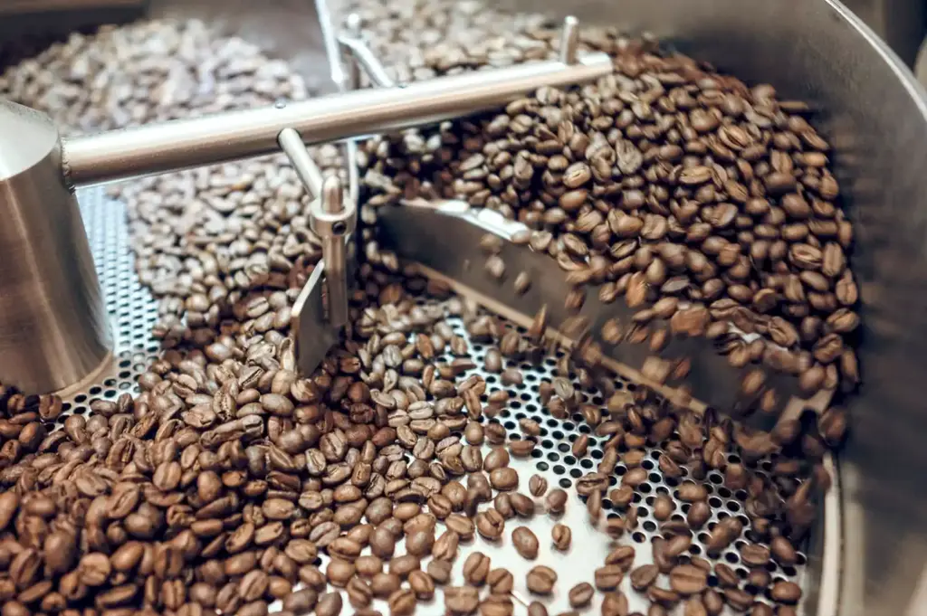 Coffee beans being processed in a modern industrial roaster, highlighting the meticulous production method used for high-quality decaffeinated coffee.