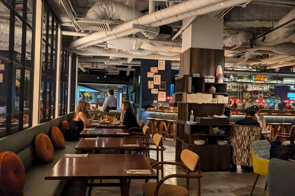 Warm, industrial-chic dining room of Wild Honey at Mandarin Gallery, showing comfortable seating arrangements and a relaxed ambiance perfect for brunch in Singapore.