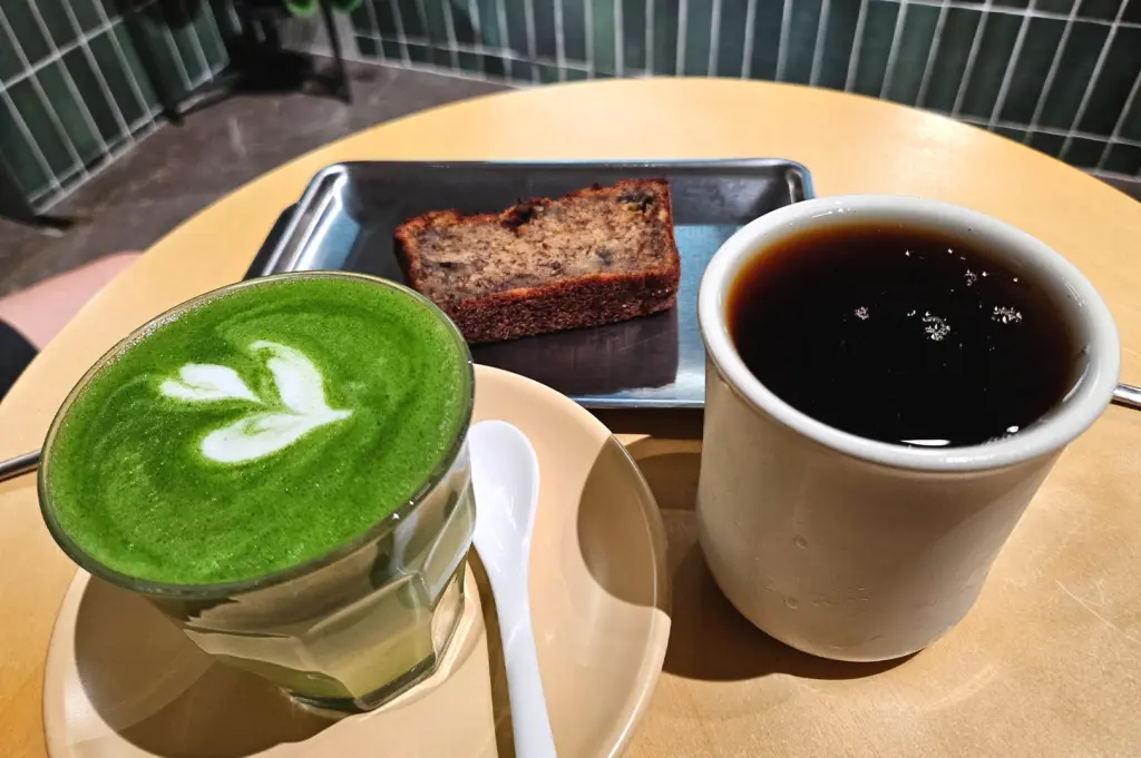 A relaxing coffee break at Kyuukei Coffee featuring a vibrant matcha latte and a slice of moist banana bread, capturing the cosy café experience in Singapore