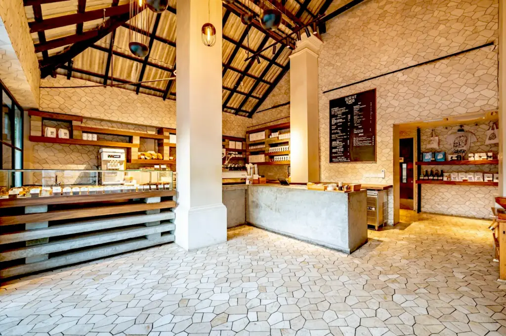 Wide-angle shot of the rustic-industrial interior of Burnt Ends Bakery, displaying the menu board, concrete service counter, and unique stone-tiled floor.