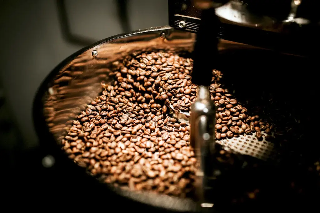 A scene of coffee beans swirling in a professional coffee roaster, detailing the roasting stage of decaffeinated coffee production.