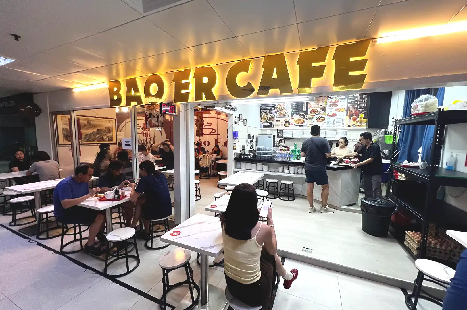 Exterior facade and bustling dining area of Bao Er Cafe at Fortune Centre in Singapore, serving traditional comfort food.