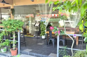 The plant-filled glass storefront of The Garden Slug cafe in Telok Kurau, welcoming visitors to a relaxed neighborhood dining spot.