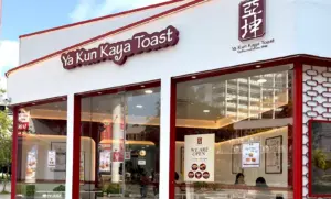 Exterior storefront of a Ya Kun Kaya Toast traditional coffee stall in Singapore, featuring white and maroon branding and large glass windows.