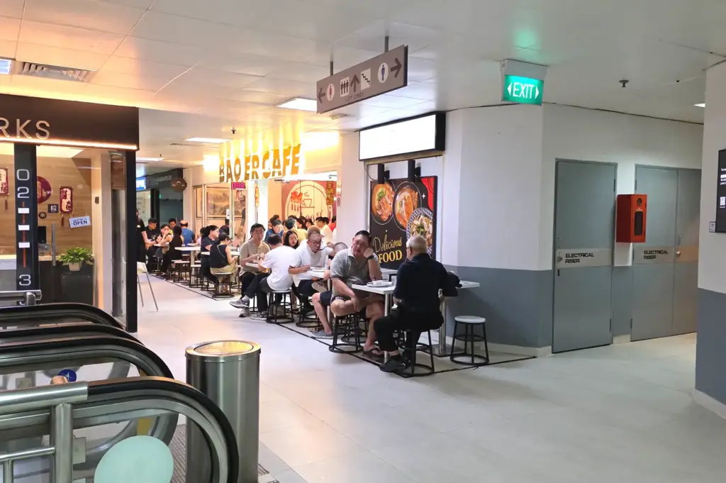 Hallway view leading to Bao Er Cafe at Fortune Centre, showing indoor and corridor seating filled with diners.