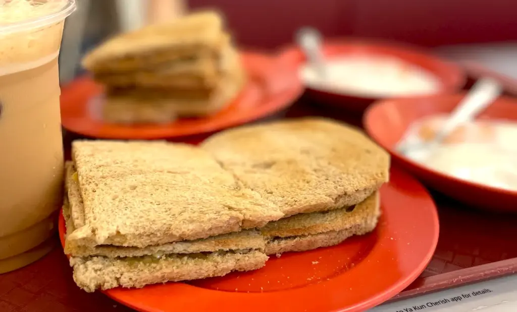 Close-up of a traditional Singaporean breakfast set at Ya Kun Kaya Toast featuring crisp kaya toast, soft-boiled eggs, and coffee.