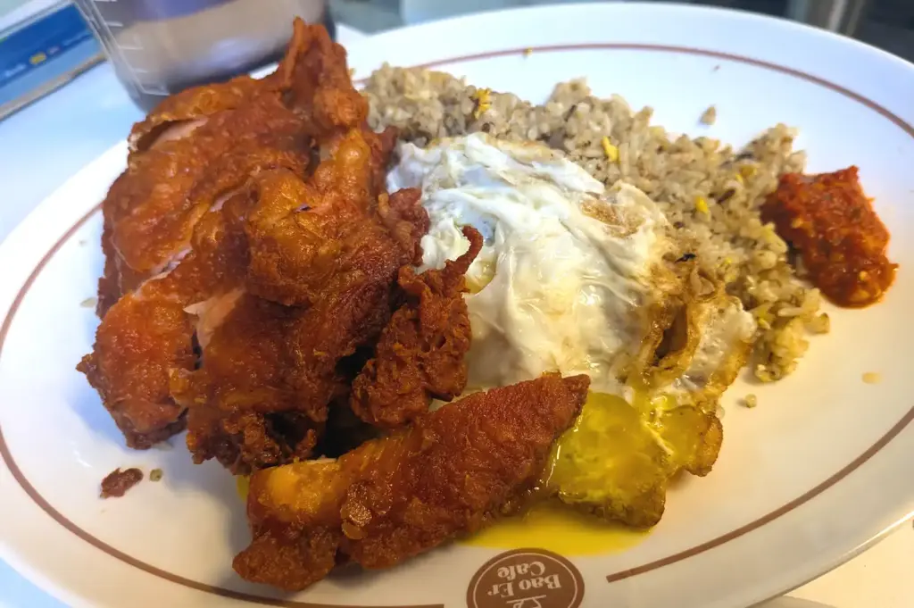 Crispy fried chicken cutlet served with fried rice and a runny fried egg at Bao Er Cafe Singapore.