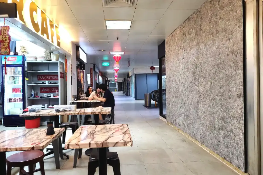Corridor dining tables set up outside Bao Er Cafe along the hallway of Fortune Centre in Singapore.