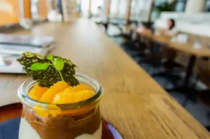 A close up shot of a vegan drink on a wooden table with a cafe interior blurred in the background.
