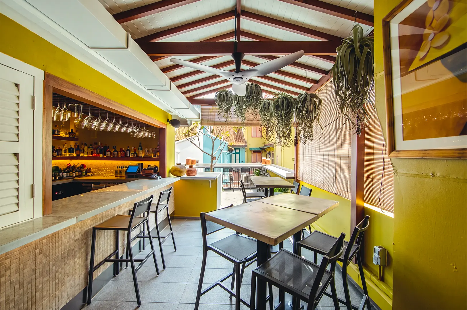 Kafe Utu interior with a bright sunlight filtering through inside the yellow and white themed walls and ceiling accented by brown support beams and furniture.