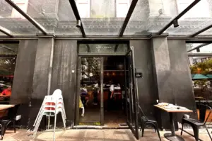 The front entrance of Toby's Estate Coffee Roasters in Robertson Quay, Singapore, featuring modern glass architecture and outdoor seating.