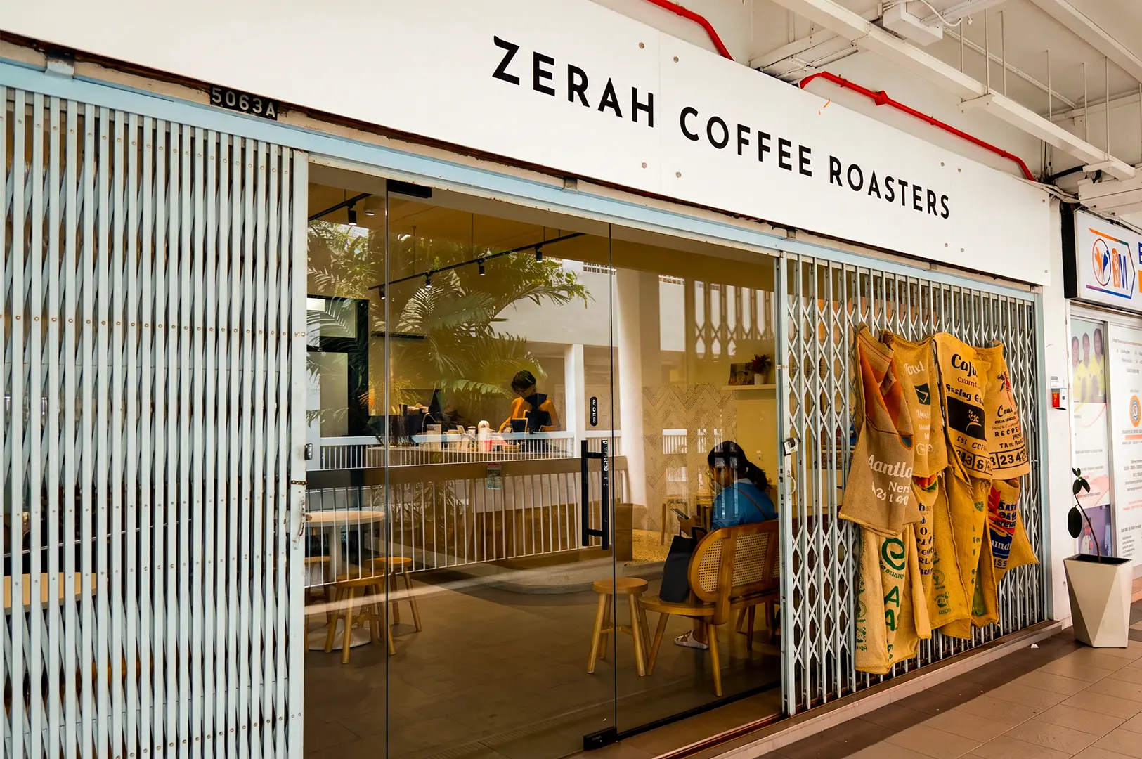 Zerah Coffee Roasters exterior with its minimalist logo signage on top and a glass entrance revealing its cozy interior.