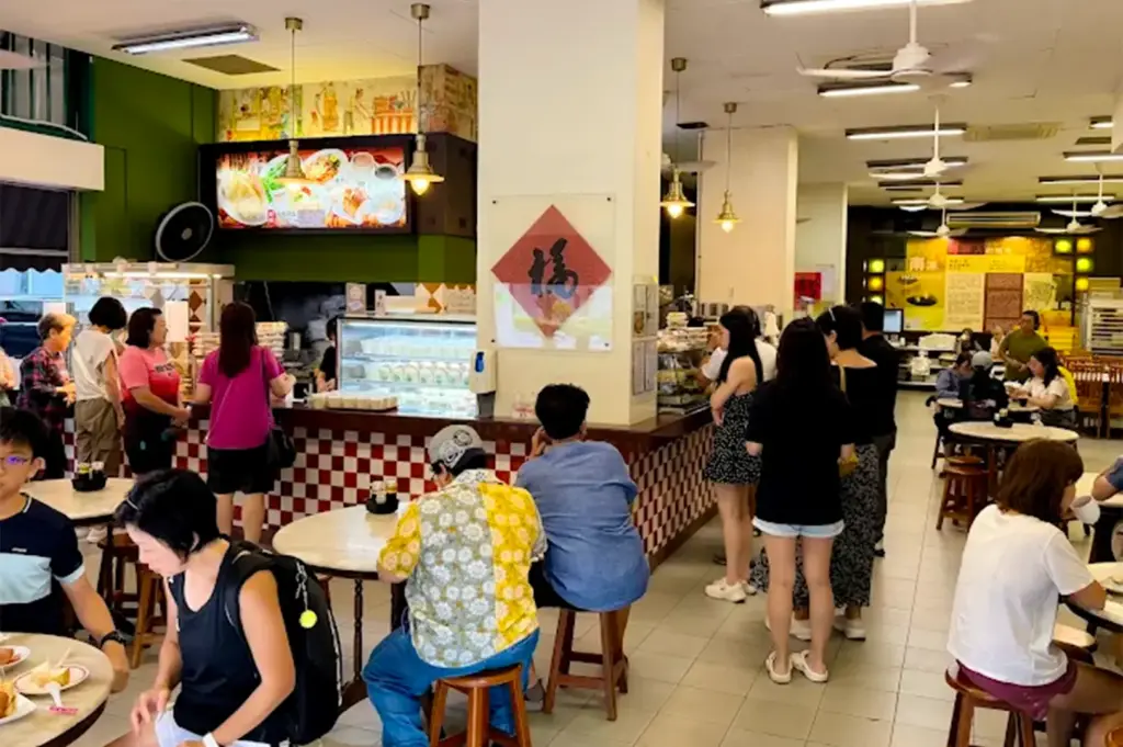 YY Kafei Dian interior with retro themed wall designs, menu, and tables and chars with busy customers dining and ordering.