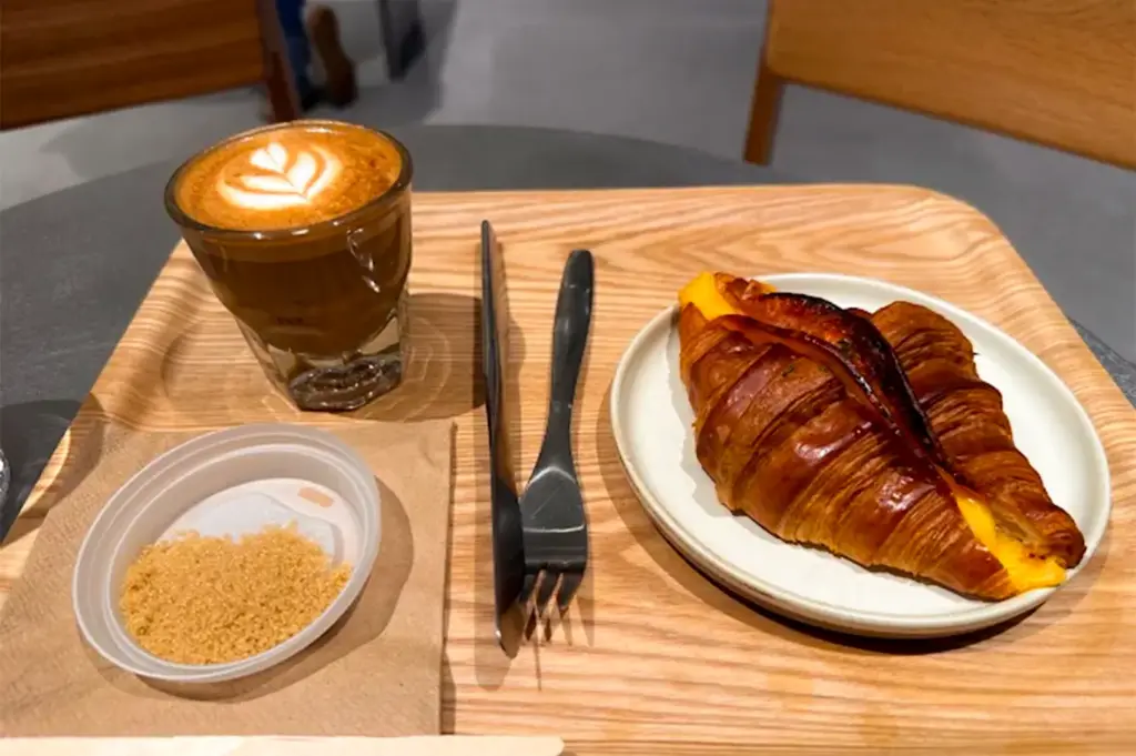 High angle shot of coffee and pastry menu items on a wooden tray served at Blue Bottle Coffee.