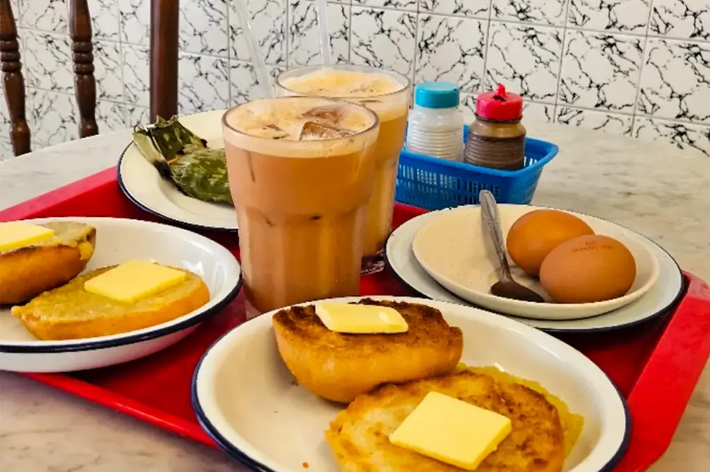 Chin Mee Chin kaya bun served in white platters together with two glasses of coffee.