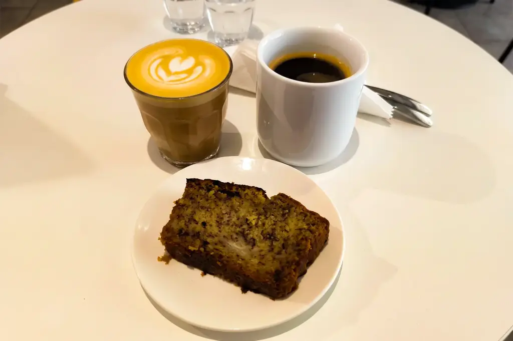 Two different coffee cups and a bread served on a white plate on a white round table at Zerah Coffee Roasters.