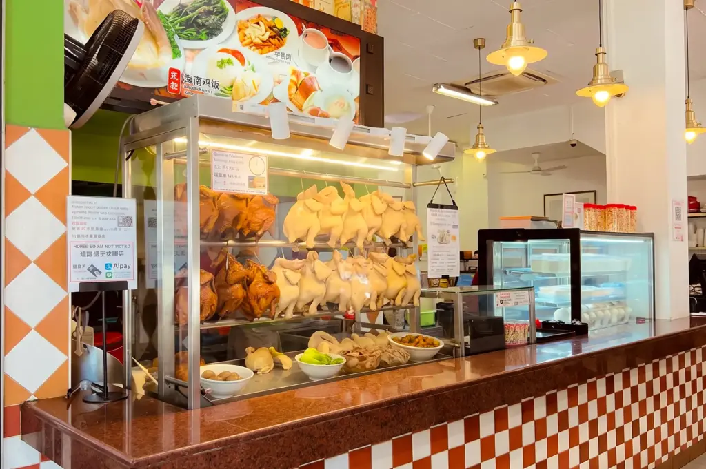YY Kafei Dian counter with fresh chicken in the glass display and menu items displayed above, lit by yellow hanging lights.