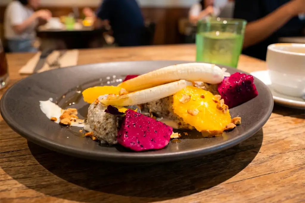Medium shot of an African cuisine menu item served at Kafe Utu arranged on a black plate on a wooden table.