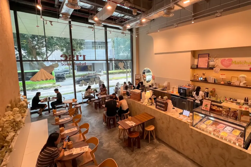 Rise Bakehouse high angle interior view with dining customers seating at tables and chairs scattered around the interior and the counter on the right.
