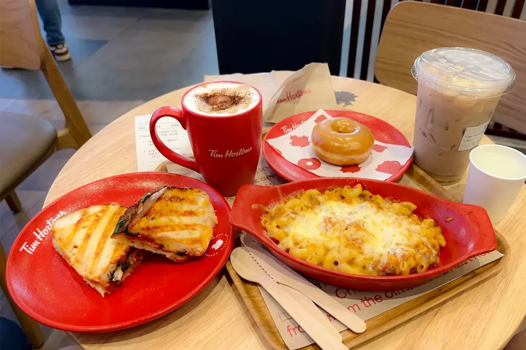 Tim Hortons menu items including sandwiches, pasta, donuts, and coffee served in red mugs and plates.